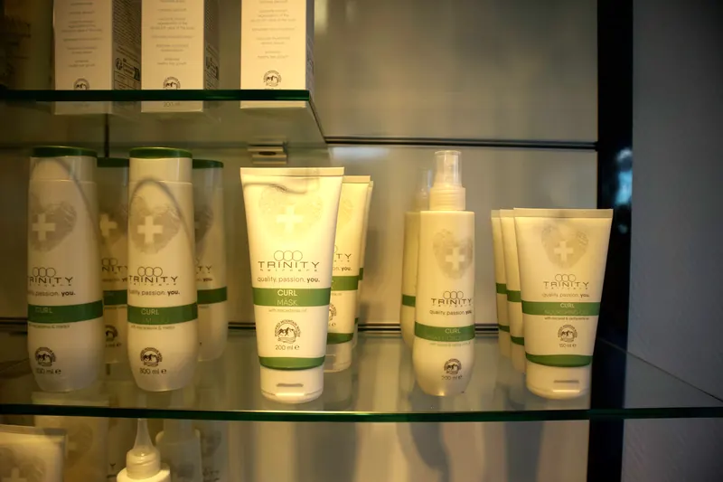 Pflegeprodukte von TRINITY haircare auf einem Glasregal